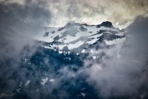 Snow-covered mountain peaks partially obscured by fog and clouds.